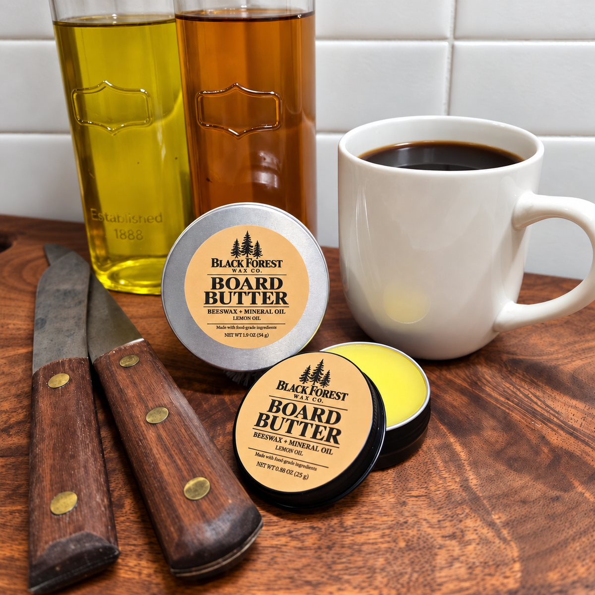 Black Forest Wax Co. Board Butter in two sizes on a wooden cutting board beside coffee